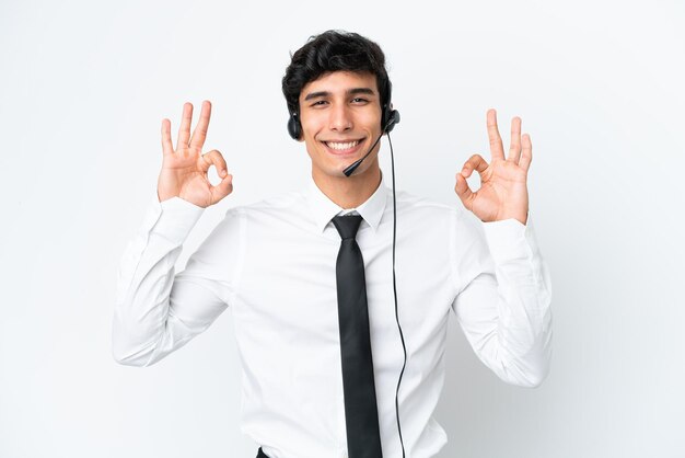 Telemarketeer man aan het werk met een headset geïsoleerd op een witte achtergrond met een ok teken met vingers