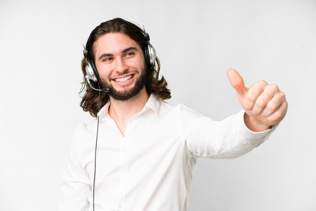 Telemarketeer man aan het werk met een headset over geïsoleerde witte achtergrond met een duim omhoog gebaar