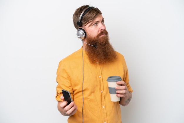 Telemarketeer man geïsoleerd op een witte achtergrond met koffie om mee te nemen en een mobiel
