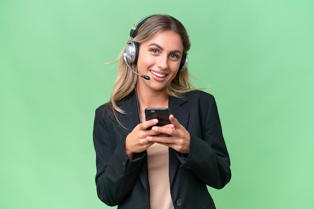 Telemarketeer mooie Uruguayaanse vrouw die werkt met een headset over een geïsoleerde achtergrond die een bericht verzendt met de mobiel