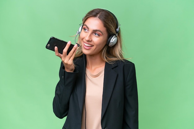 Telemarketeer mooie Uruguayaanse vrouw die werkt met een headset over een geïsoleerde achtergrond en een gesprek voert met de mobiele telefoon met iemand