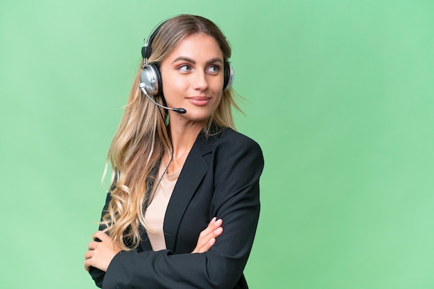 Telemarketeer mooie Uruguayaanse vrouw die werkt met een headset over geïsoleerde achtergrond met gekruiste armen en gelukkig