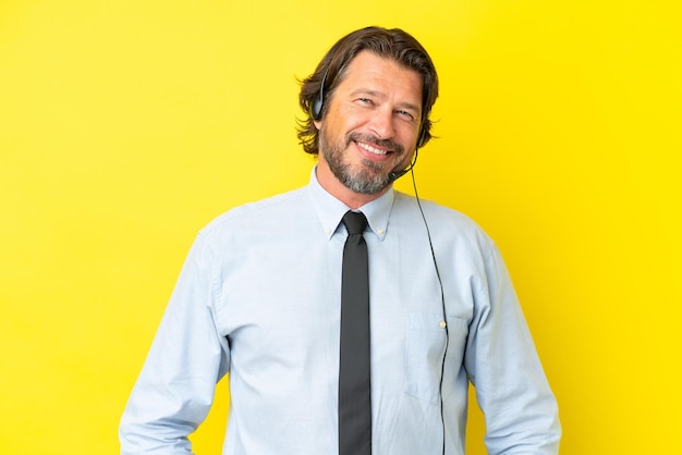 Foto telemarketeer nederlandse man aan het werk met een headset geïsoleerd op gele achtergrond lachen