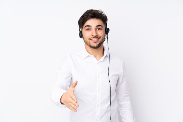 Telemarketer Arabian man working with a headset isolated on white wall handshaking after good deal