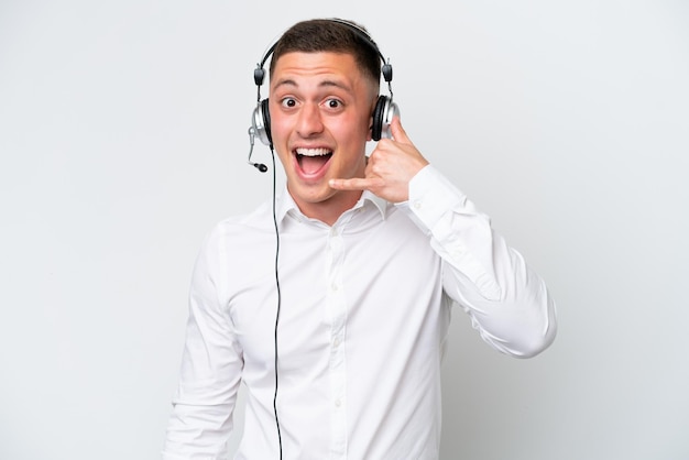 Telemarketer Brazilian man working with a headset isolated on white background making phone gesture Call me back sign