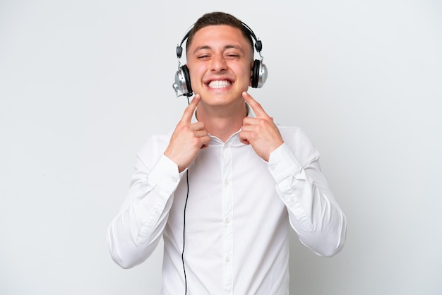 Telemarketer Brazilian man working with a headset isolated on white background smiling with a happy and pleasant expression