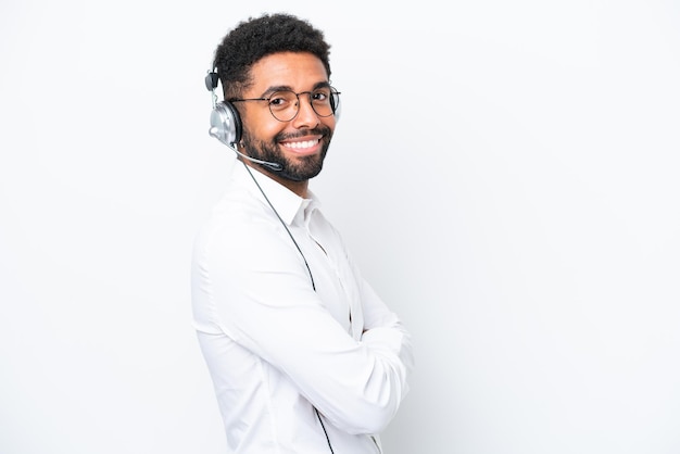 Telemarketer Brazilian man working with a headset isolated on white background with arms crossed and looking forward