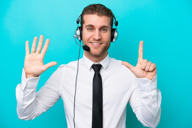 Telemarketer caucasian man working with a headset isolated on blue background counting seven with fingers