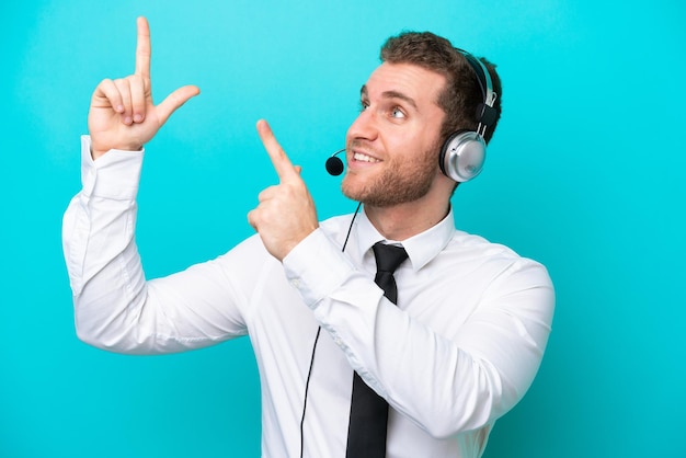 Telemarketer caucasian man working with a headset isolated on blue background pointing with the index finger a great idea