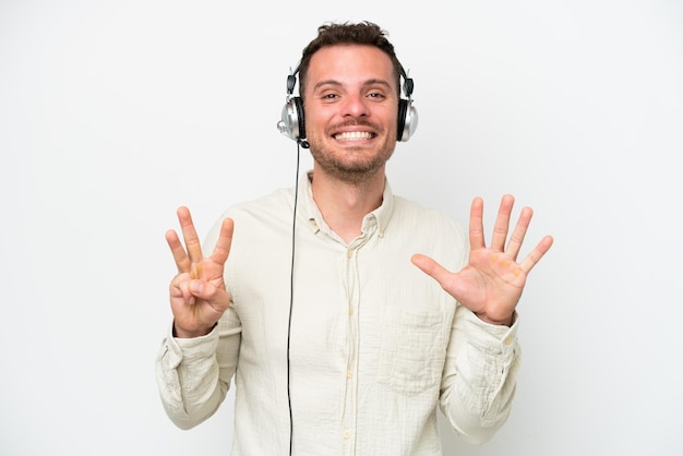 Telemarketer caucasian man working with a headset isolated on white background counting eight with fingers