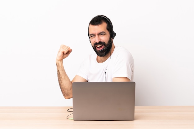 Telemarketer caucasian man working with a headset and with laptop celebrating a victory.