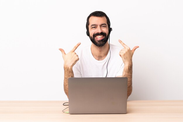 Telemarketer caucasian man working with a headset and with laptop giving a thumbs up gesture.