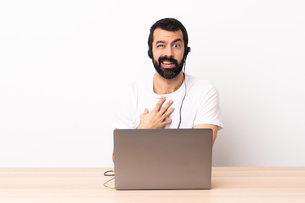 Telemarketer caucasian man working with a headset and with laptop pointing to oneself