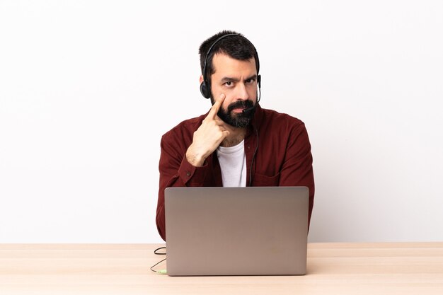 Telemarketer caucasian man working with a headset and with laptop showing something.