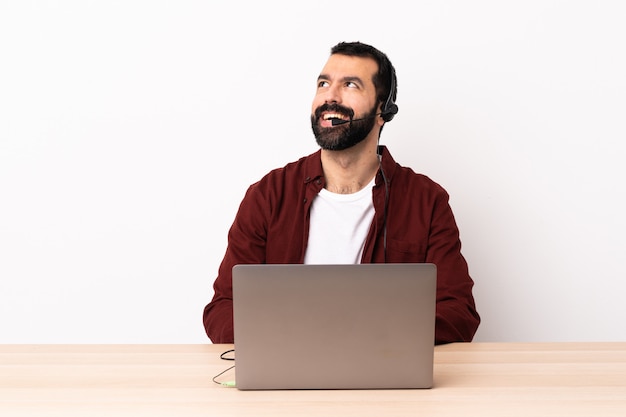 Telemarketer caucasian man working with a headset and with laptop thinking an idea while looking up