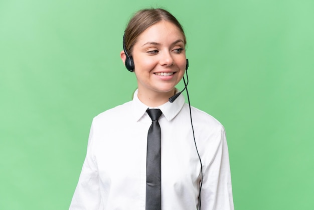 Telemarketer caucasian woman working with a headset over isolated background with happy expression