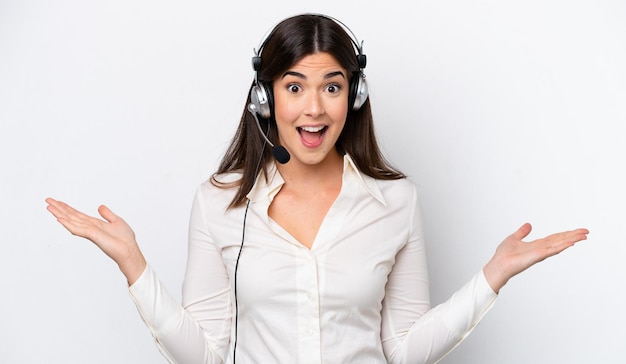 Telemarketer caucasian woman working with a headset isolated on white background with shocked facial expression