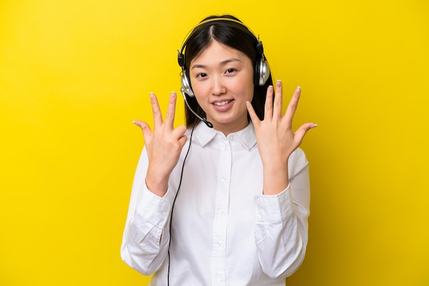 Telemarketer Chinese woman working with a headset isolated on yellow background counting eight with fingers