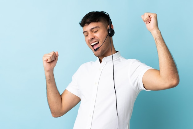 Telemarketer Colombian man working with a headset over isolated celebrating a victory