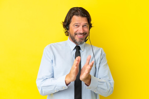 Photo telemarketer dutch man working with a headset isolated on yellow background applauding after presentation in a conference