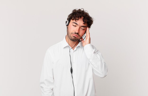 Telemarketer si sente annoiato, frustrato e assonnato dopo un compito noioso, noioso e noioso, tenendo il viso con la mano