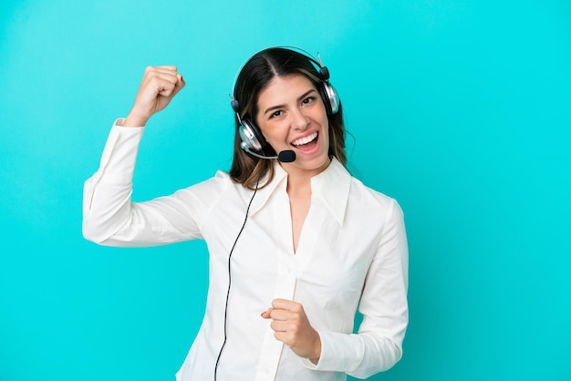 Telemarketer Italian woman working with a headset isolated on blue background celebrating a victory