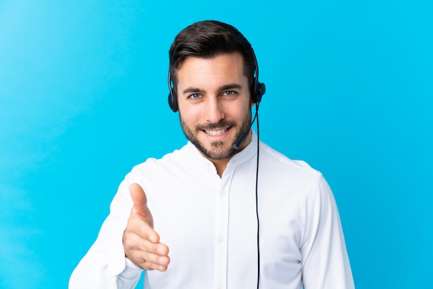 Foto uomo di telemarketer che lavora con un auricolare sopra handshake blu dopo un buon affare