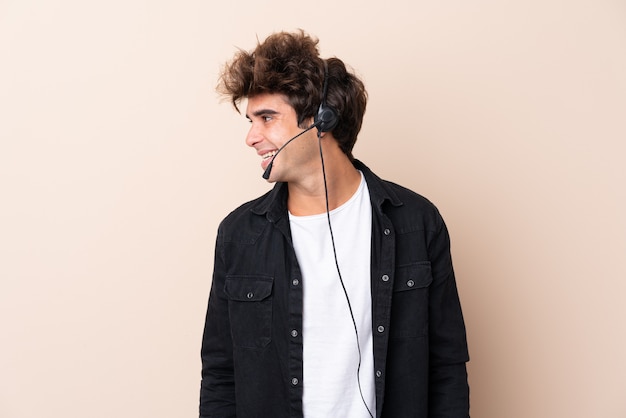 Telemarketer man working with a headset over isolated wall looking to the side