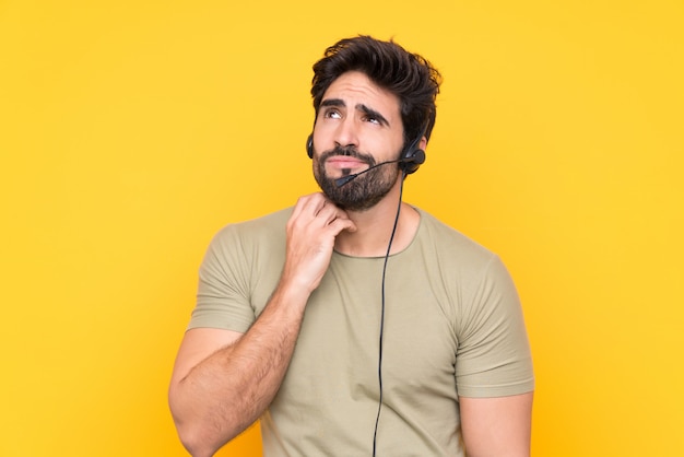Telemarketer man working with a headset over isolated wall