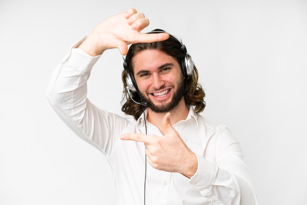 Telemarketer man working with a headset over isolated white background focusing face Framing symbol