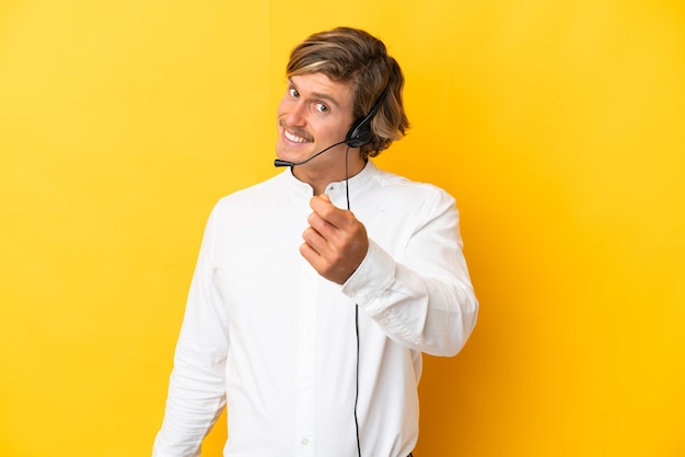 Telemarketer man working with a headset isolated on yellow making money gesture