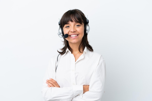 Foto telemarketer donna di razza mista che lavora con un auricolare isolato su sfondo bianco mantenendo le braccia incrociate in posizione frontale