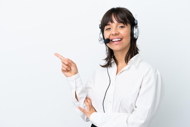 Telemarketer mixed race woman working with a headset isolated on white background pointing finger to the side