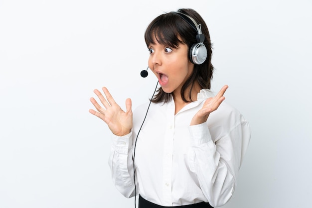 Telemarketer mixed race woman working with a headset isolated on white background with surprise facial expression