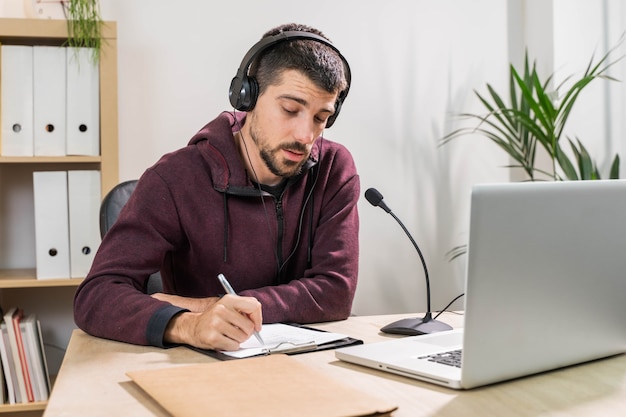 Telemarketer o podcast uomo che lavora con il laptop e parla su un auricolare con maschera facciale in ufficio