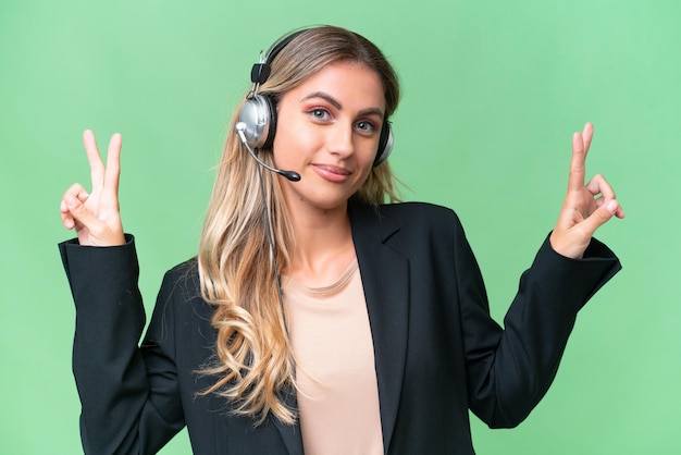 Telemarketer pretty Uruguayan woman working with a headset over isolated background showing victory sign with both hands