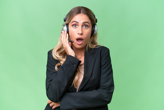 Telemarketer pretty Uruguayan woman working with a headset over isolated background surprised and shocked while looking right