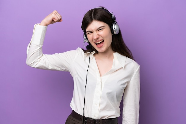 Telemarketer Russian woman working with a headset isolated on purple background doing strong gesture