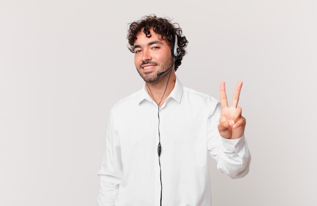 Telemarketer smiling and looking friendly showing number two or second with hand forward counting down