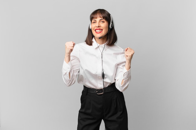 telemarketer woman feeling shocked, excited and happy, laughing and celebrating success, saying wow!