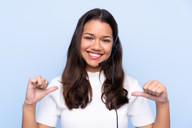 Telemarketer woman working with a headset over isolated wall