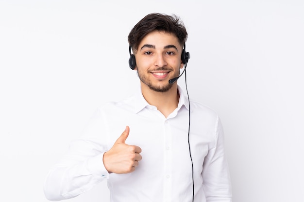 Telemarketer working with a headset isolated on white wall giving a thumbs up gesture