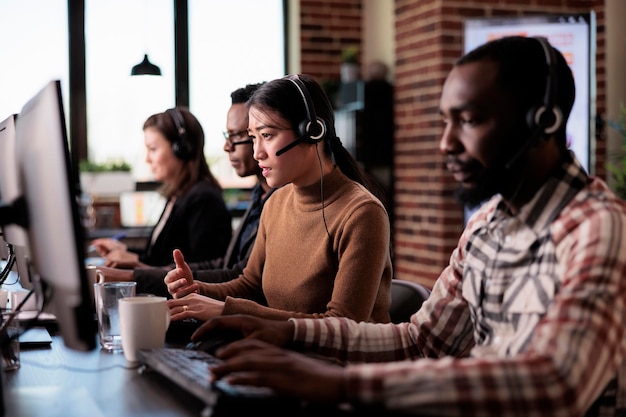 Photo telemarketing assistant working at customer service helpdesk, talking to clients on helpline support at call center. sales consultant using remote telecommunication assistance in office.