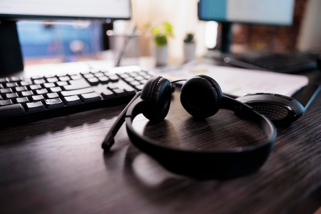 Telemarketing client service equipment on helpdesk in office, telework headset with microphone. Call center customer support helpline on reception desk with computers. Close up.