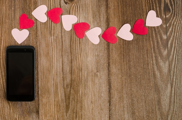 Telephone emitting signal in the shape of hearts on wooden table