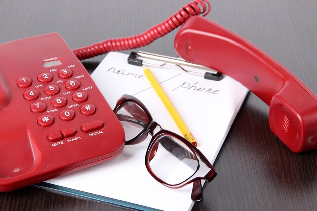 telephone and notepad and other items on wooden background