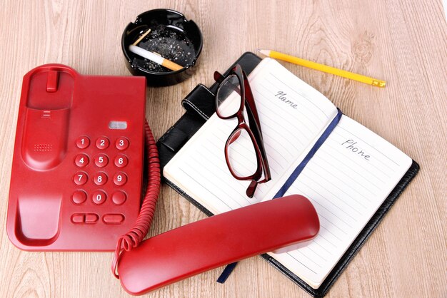 telephone and notepad and other items on wooden background