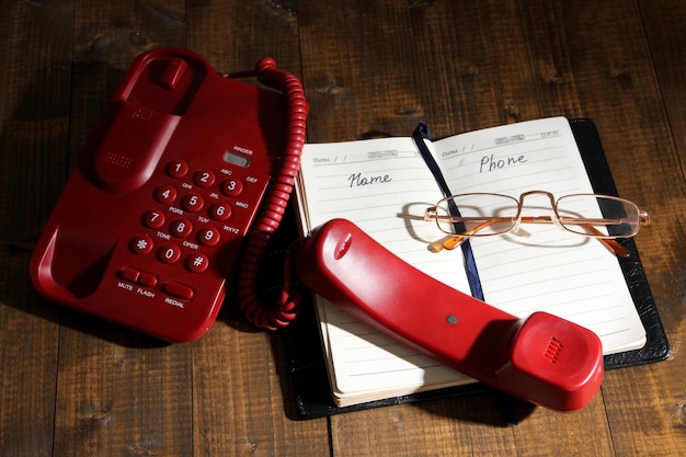 telephone and notepad and other items on wooden background