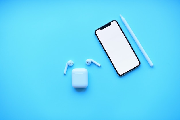 Photo telephone with pencil and air pods on blue background