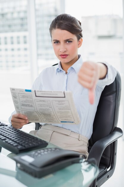 Teleurgestelde elegante bruine haired onderneemster die een krant leest